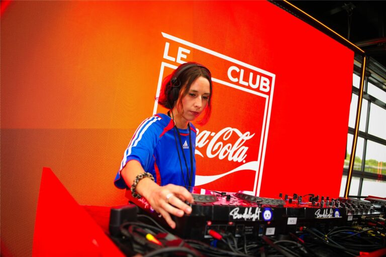 DJ en maillot de l'équipe de France devant le logo Le Club Coca-Cola