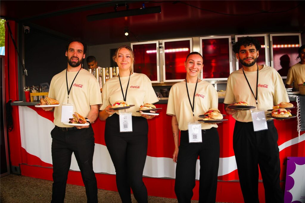L'équipe du Club Coca-Cola en tee-shirts crème servant des plats