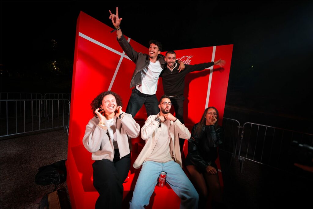 Groupe d'invités posant dans le décor photo rouge du Club Coca-Cola