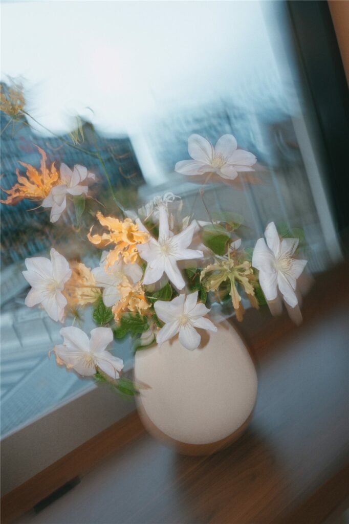 Bouquet de fleurs blanches et orangées devant une fenêtre lors de la soirée Merit