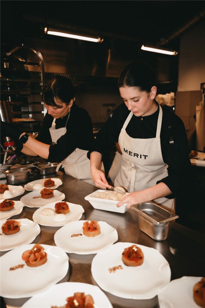 Dressage des assiettes en cuisine par l'équipe en tablier Merit
