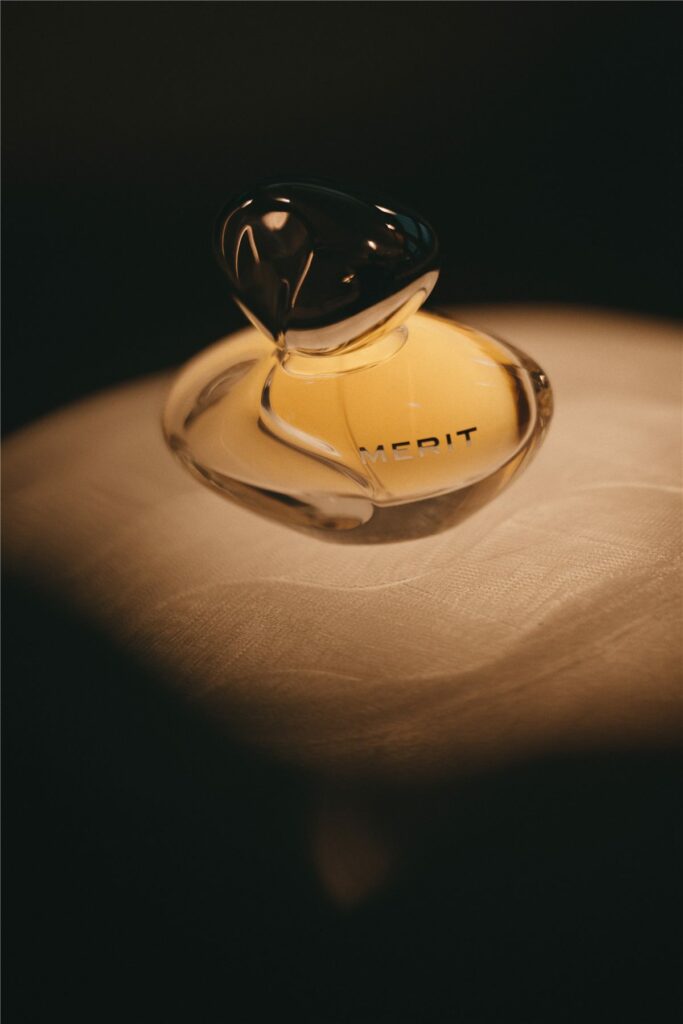 Flacon du parfum New Wave de Merit mis en lumière sur un socle