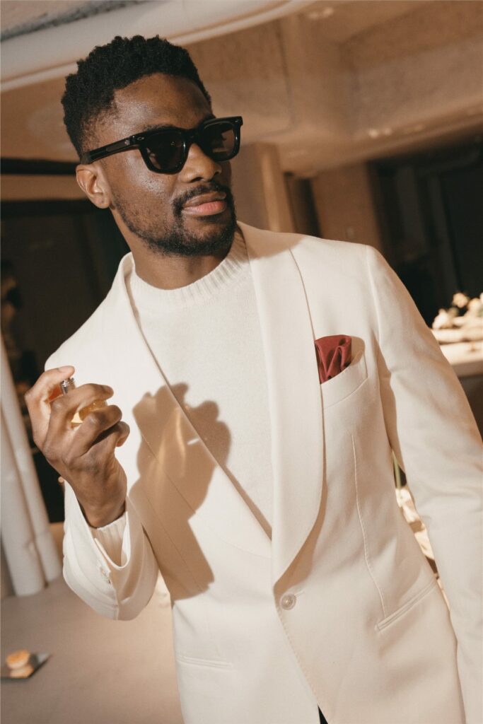 Invité en costume blanc et lunettes de soleil découvrant le parfum
