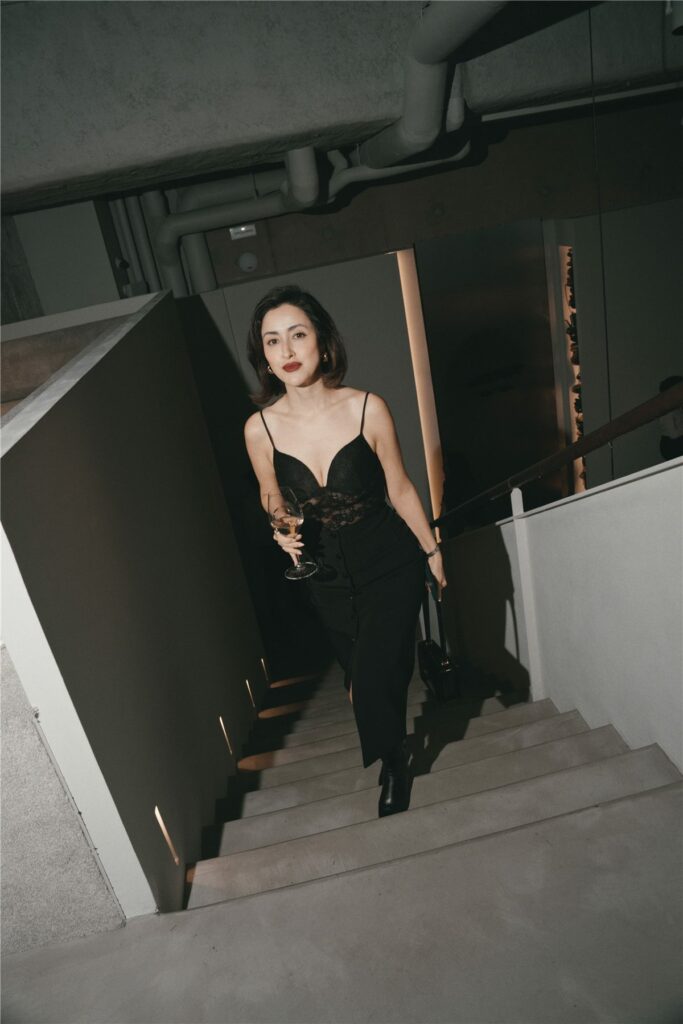 Invitée en robe noire montant l'escalier du Grand Atelier
