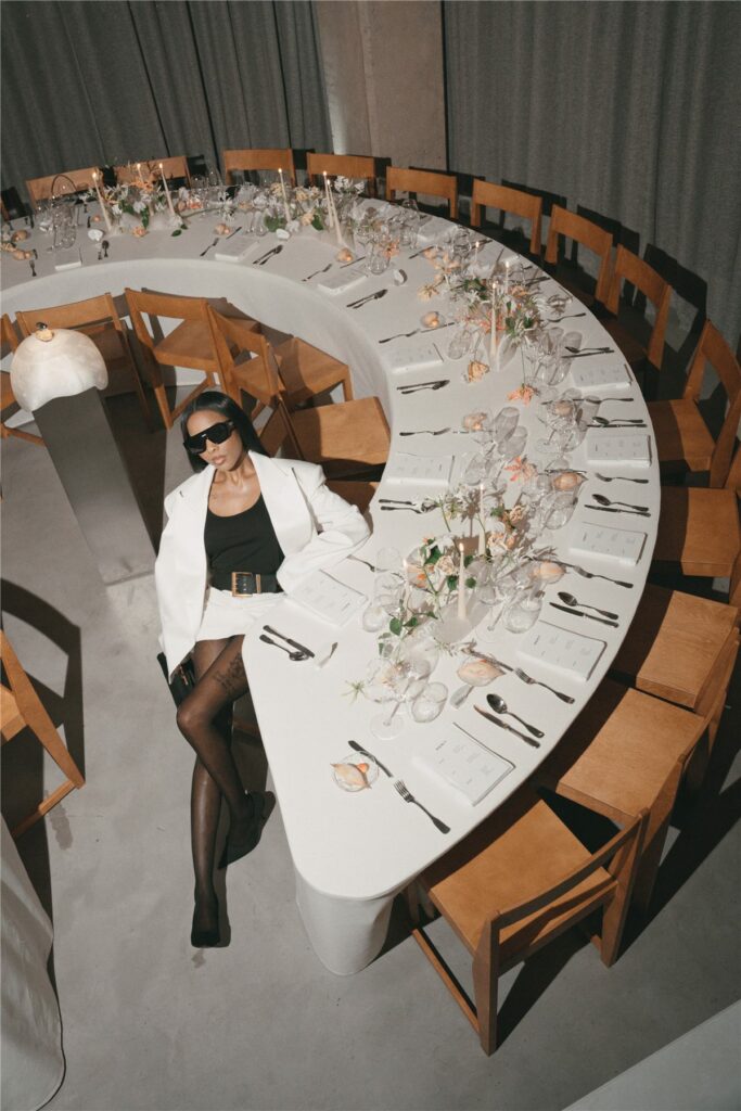 Grande table ronde dressée pour le dîner Merit New Wave, une invitée assise en premier plan