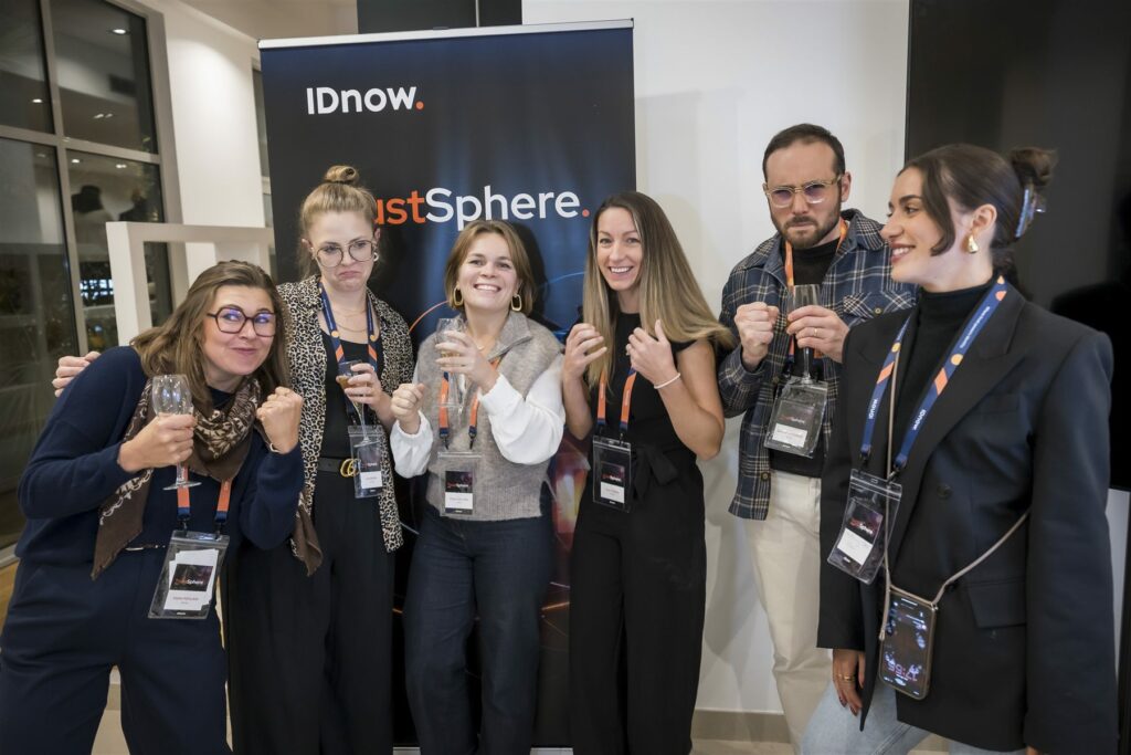 Groupe de participants posant devant le kakémono IDnow TrustSphere