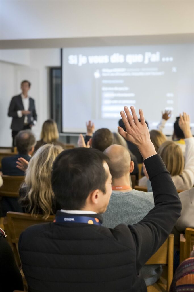 Un participant lève la main pour poser une question pendant la conférence