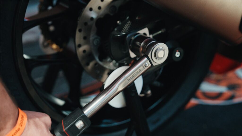Gros plan sur une clé dynamométrique serrant la roue d'une moto de course