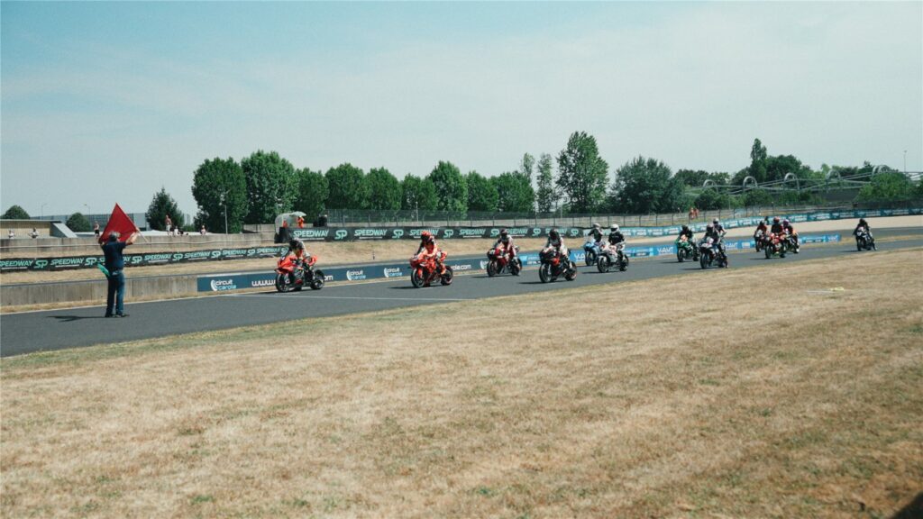 Motos alignées derrière un commissaire agitant des drapeaux sur le Circuit Carole