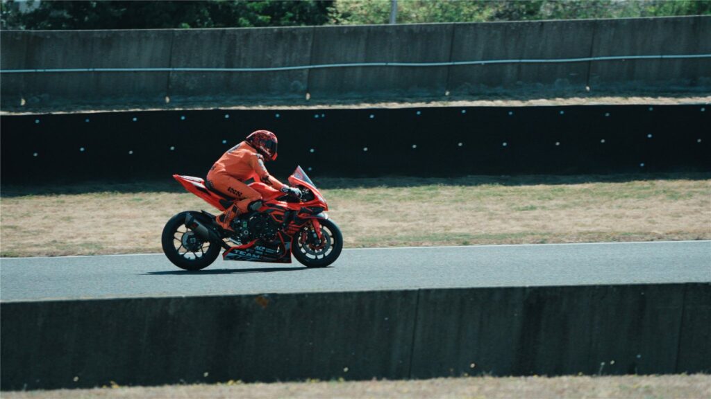 Geoffroy Dehaye en piste sur sa moto orange, penché dans un virage du Circuit Carole