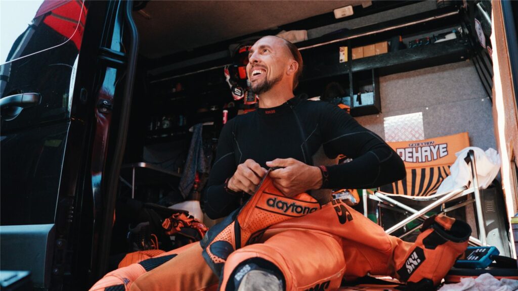 Geoffroy Dehaye rit en enfilant sa combinaison orange dans le van